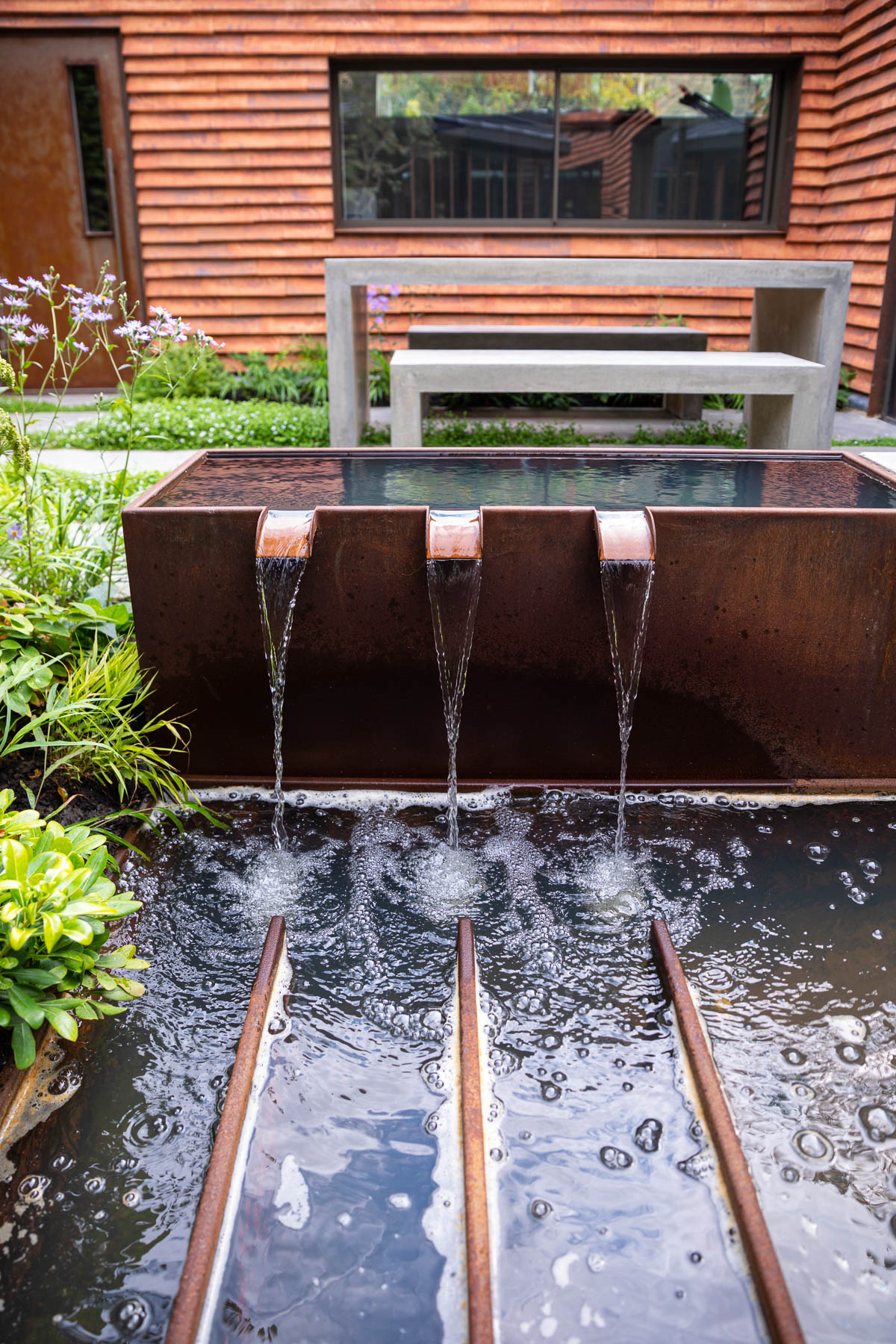 Colm Joseph Cambridge garden designer corten steel water feature tank and fountain cascade modern architecture concrete paving concrete furniture lush planting geometric lines 